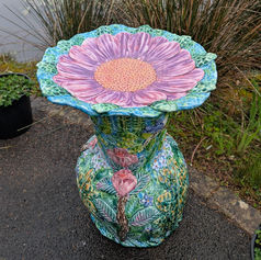 Pink Flower Bird Bath On A decorated sculptural base covered with blooms and leaves.