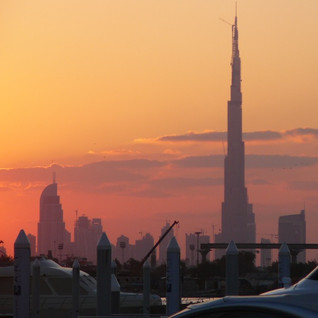 orange colours in the Dubai sky at the sunrise, very tall buildings in the city