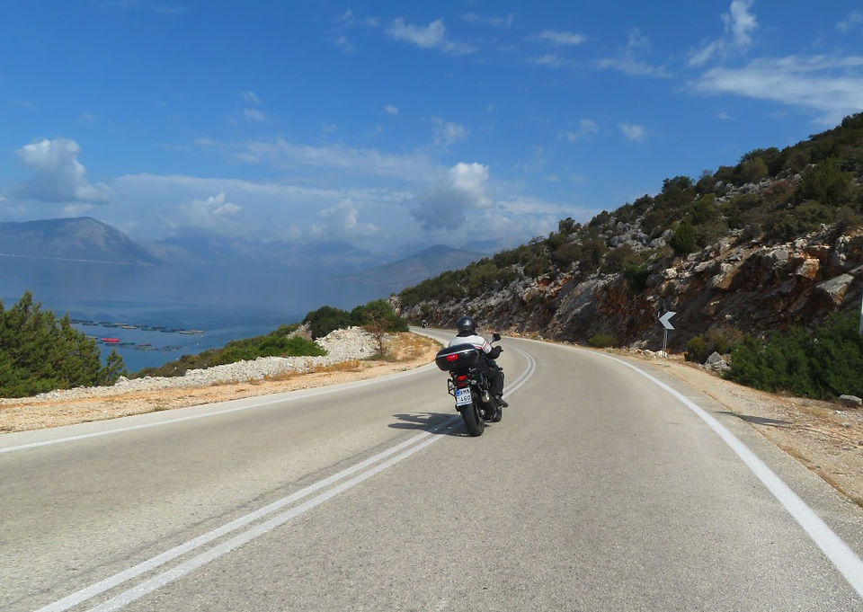 biker riding motorcycle in greece with sea view ahead