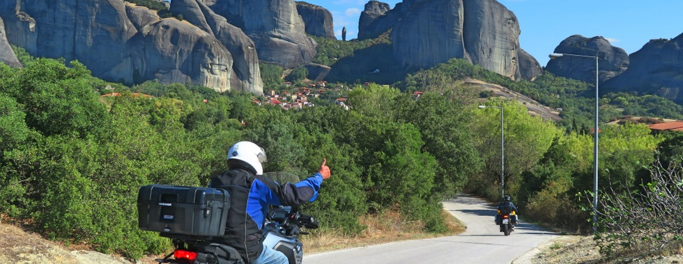 bikers riding motorcycles in the greek green countryside and rocky mountains ahead