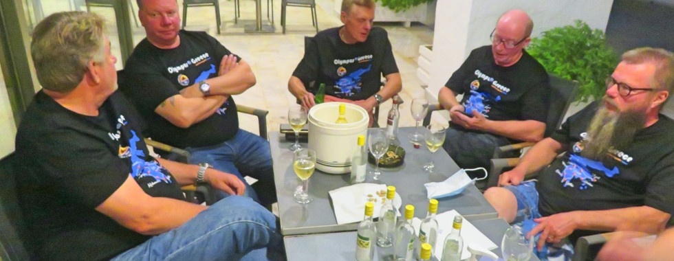 men with jeans and black t-shirt sitting around table with drinks