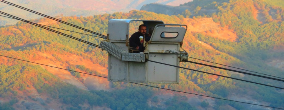 man in cable cabin between rocky mountains