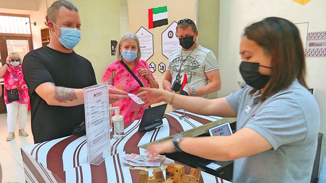 Man in black tshirt and women tourists at the change office in Dubai