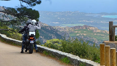 couple on motorcycle in the mountains and admiring the sea view on a motorbike tour in Corsica