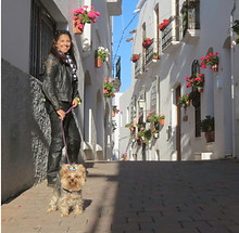 In a small white town in Andalucia Spain, biker woman smiling with her little dog. Image to illustrate PeterPanPlanet motorcycle tour in Andalusia, moottoripyörämatka espanja