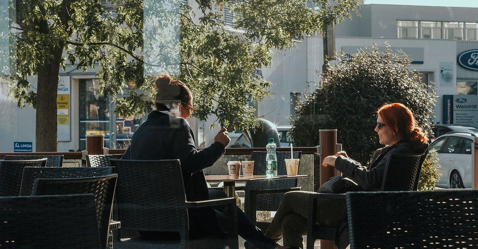 Two people in a warm, candid conversation at a sunny outdoor cafe