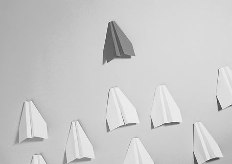 Red paper plane leading a group of pink planes on a blue background, symbolizing leadership, vision, and team alignment