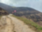 Gravel path with 10t and 20 signs curves through grassy hills under cloudy skies, conveying isolation and tranquility. AvVida.co.uk - Adventure Motorcycle Travel