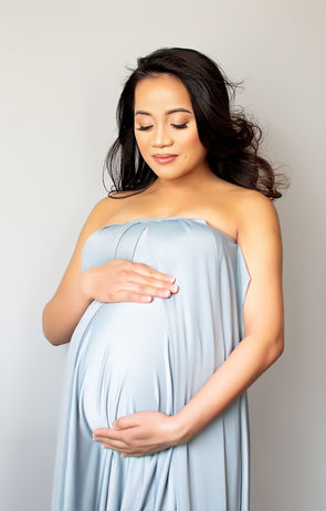 Pregnant woman in a blue dress, cradling her belly, Maternity Boudoir photography session.