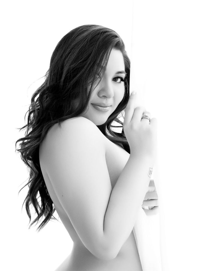 Plus size woman smiling in boudoir portrait