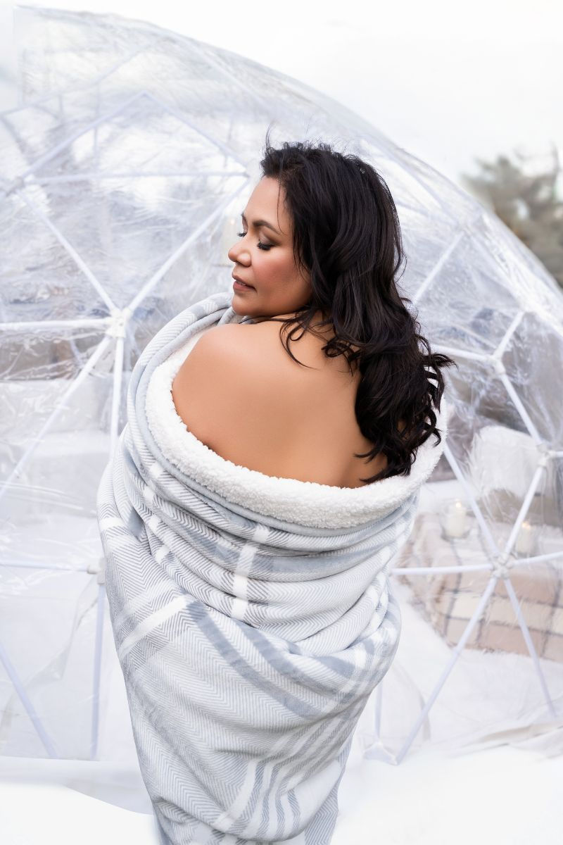 Client wrapped in a blanket in front of rooftop igloo set in Calgary.