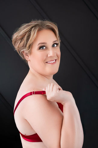 Blonde woman photographed in red lingerie against a dark studio backdrop