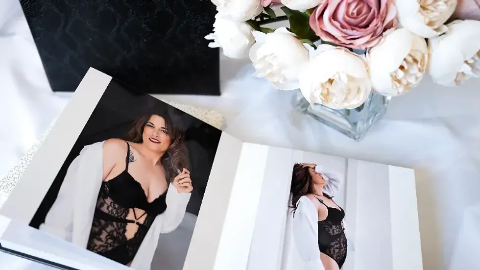Boudoir photo album with two images on a white table with flowers.