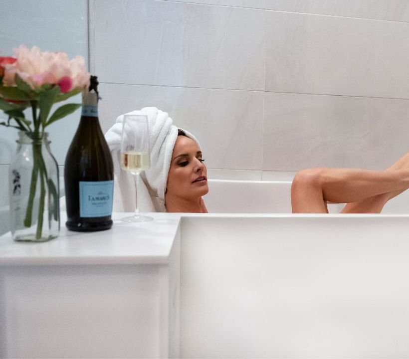 Woman in a bathtub with towel on her head and high heels.