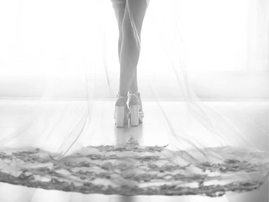 Close up of bridal shoes and veil in black and white.