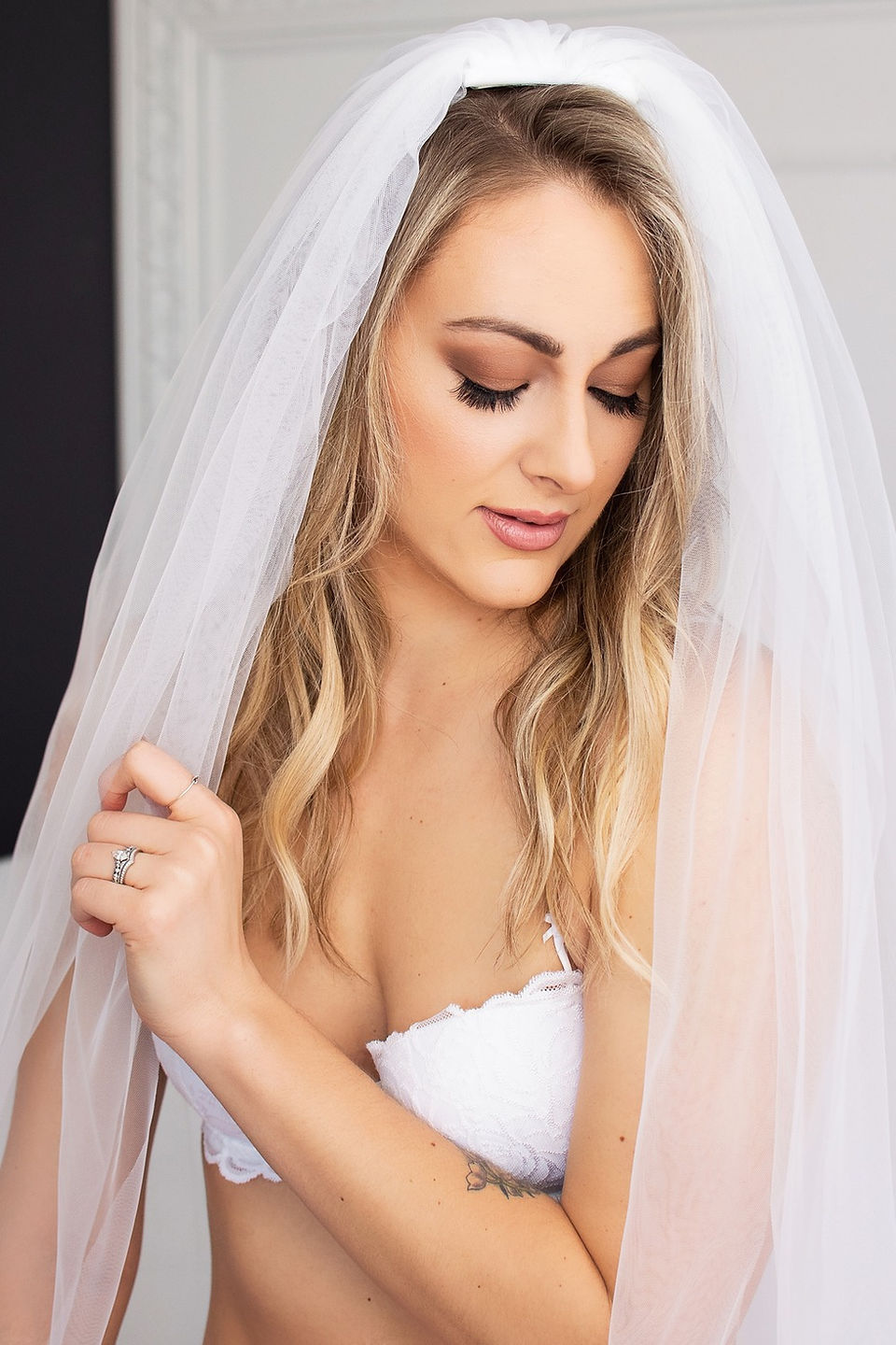 woman in white bra and wedding veil posing at boudoir shoot