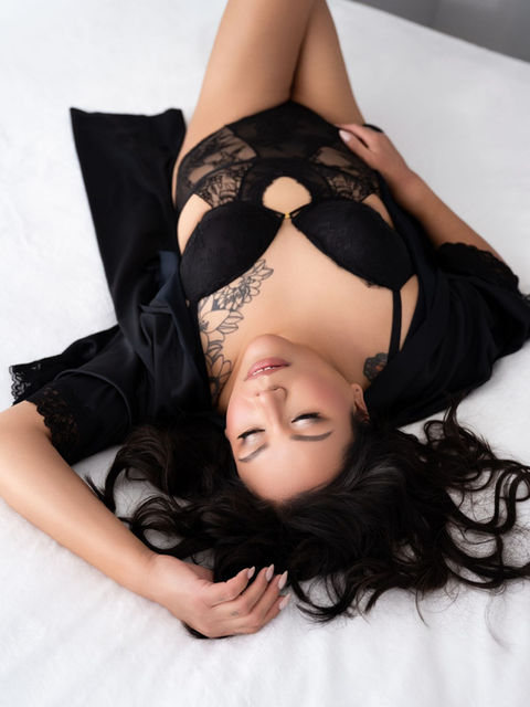 Overhead boudoir photo of a plus sized woman in black lace lingerie on white bedding in Calgary.