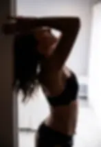 silhouette of woman with arms raised against a door frame with white boudoir bedroom in the background.