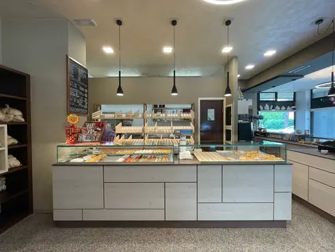 Banco espositivo di forno ristrutturato con retrobanco, mobile del pane illuminato a LED e sospensioni di design.