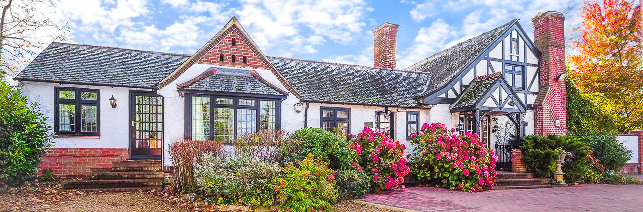 A photograph of a large tudor style house on the grounds of the hotel site.