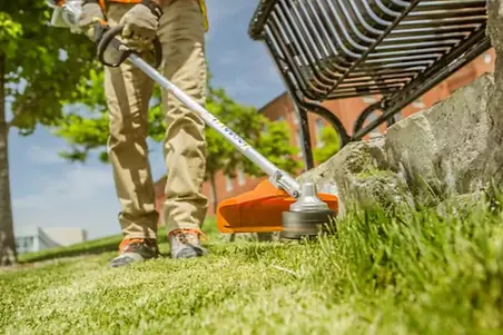 Lawn trimming and edging by Clover Property Care in Toronto West with a worker maintaining edges around garden areas.