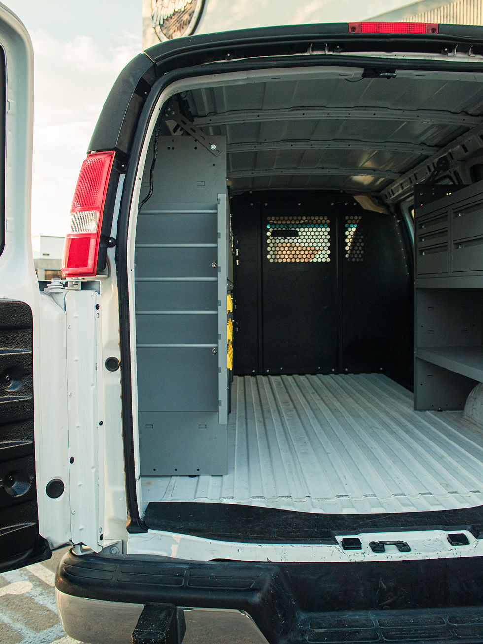 Open center aisle between Chevy cargo van storage units leading to the cab partition