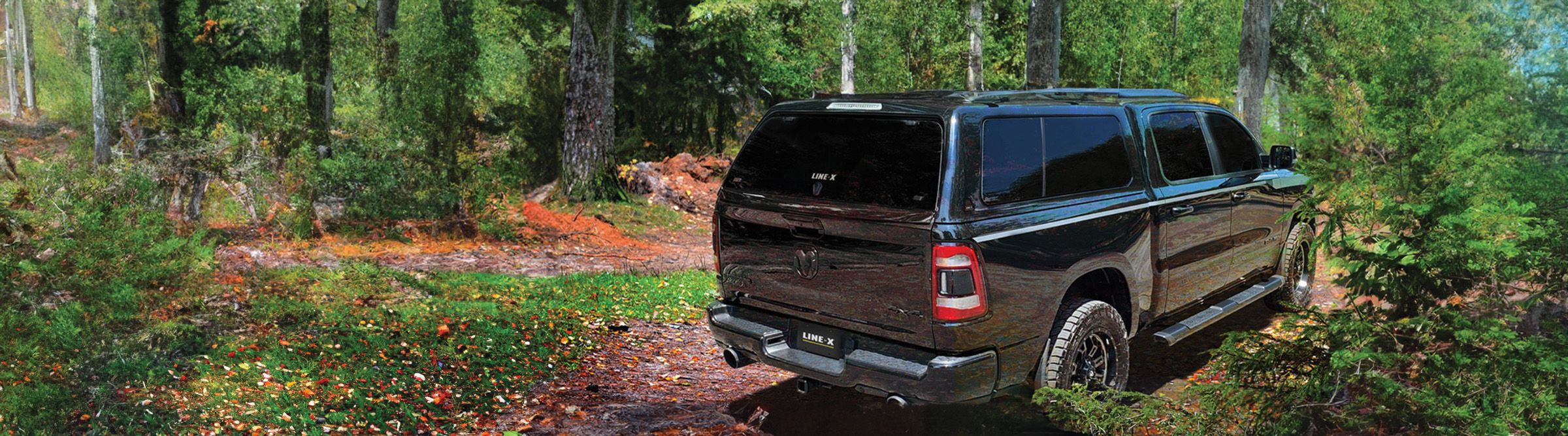 Manufacturer example of a truck fitted with a LINE-X topper on a wooded trail
