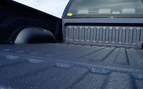 Pickup truck bed coated with a textured dark blue LINE-X spray-on bedliner.