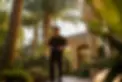 A field inspector in a black APD uniform walking through a landscaped yard with palm trees