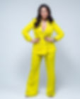 Confident woman wearing a bright yellow pantsuit, hands on hips.