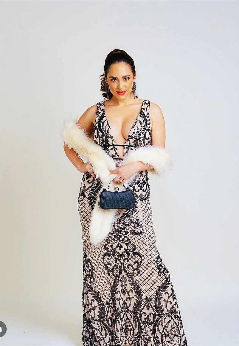 Mary Garcia posing in an elegant patterned evening dress, styled hair pulled back, holding a small handbag