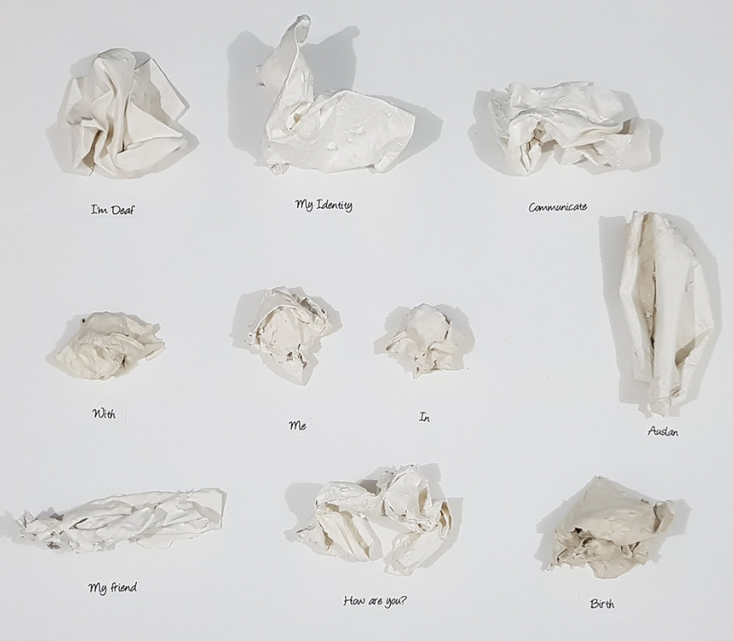 Paper Sculptures of Auslan Sign Language words. In order, they read, "I'm Deaf" "My Identity" "Communicate" "with" "me" "in" "Auslan" "My Friend" "How are you" and "Birth" 