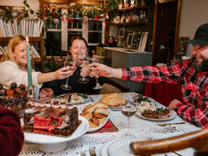 Three people at a holiday dinner table toasting glasses
