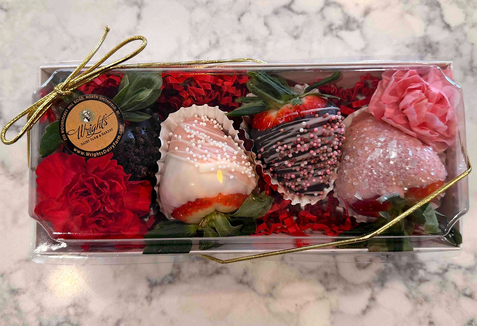 A box filled with 4 chocolate covered strawberries surrounded by flowers