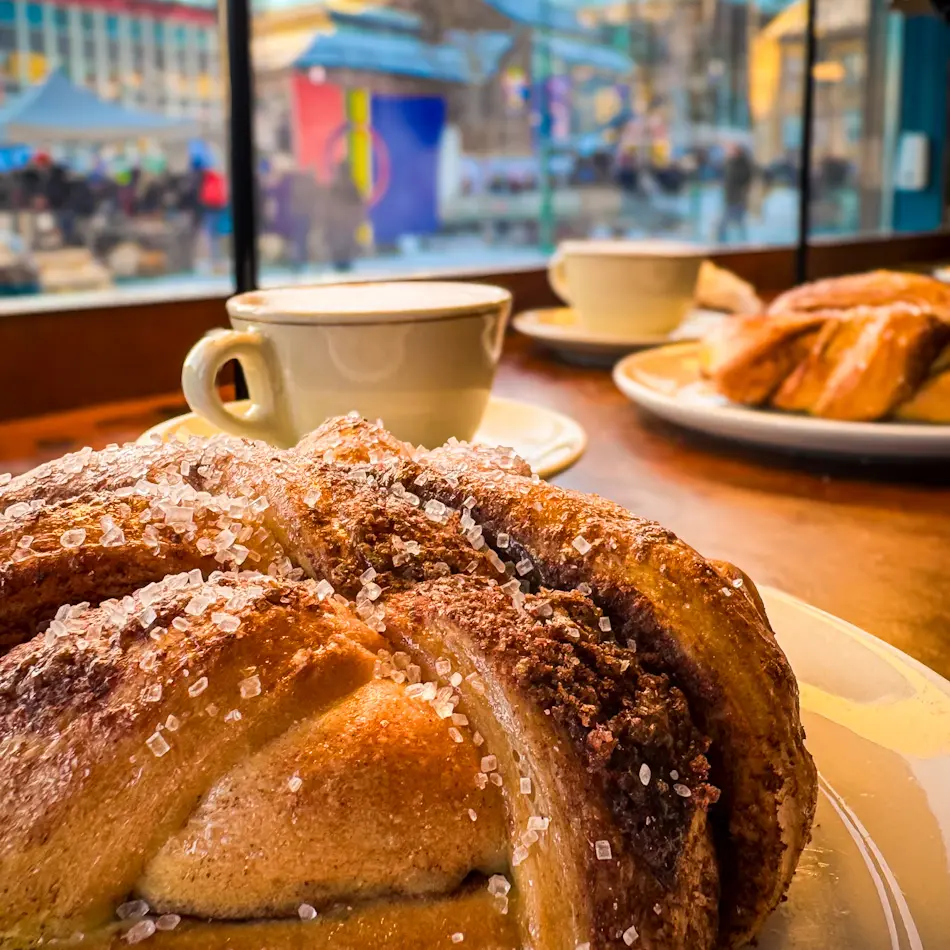 Giant cinnamon bun and coffee at Kaffebonna Stortorget, one of the best restaurants in Tromso for Nordic pastries.