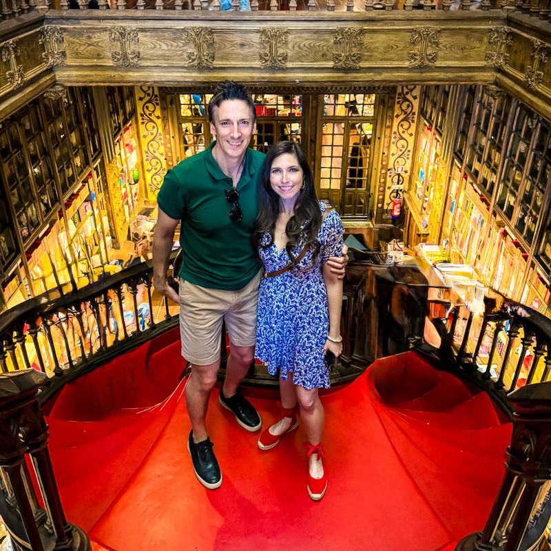 James and Shal on Livraria Lello's iconic red staircase, the most beautiful book stop in Porto, Portgual.