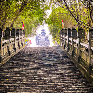 Gigantic Maitreya Buddha bronze statue at the top of a stone staircase in Bai Dinh Pagoda's grounds, one of the top things to do in Ninh Binh.