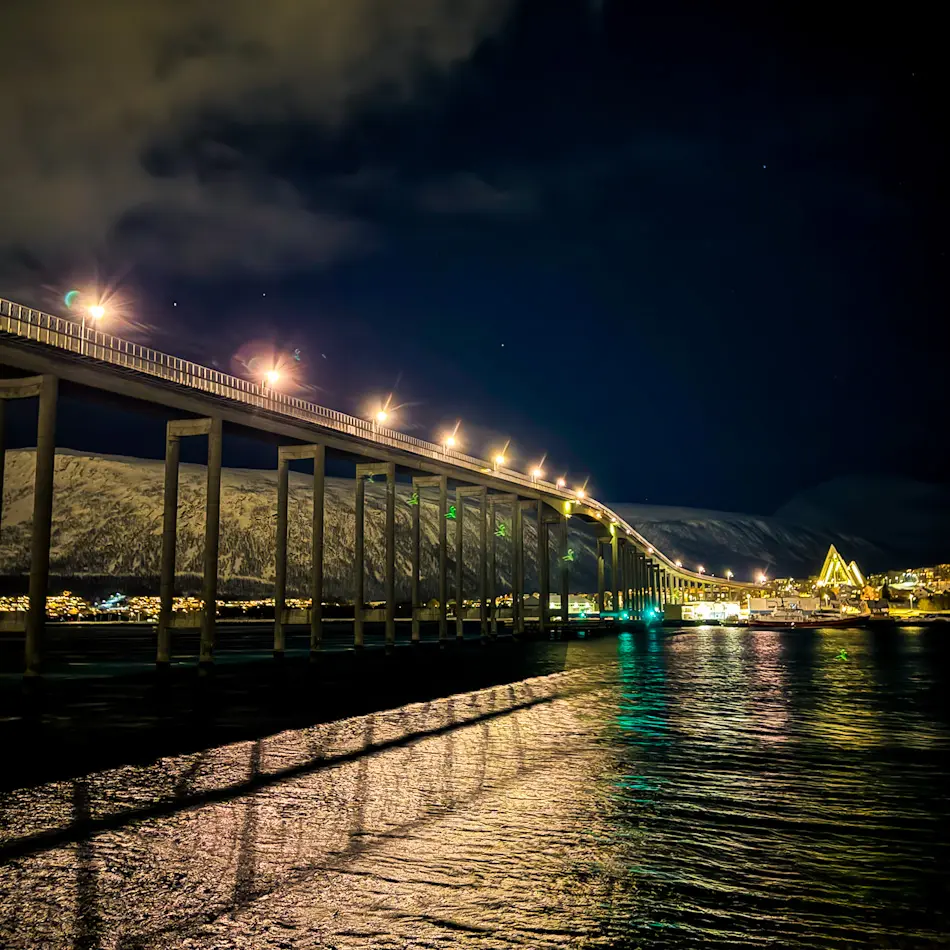 Tromsø Bridge illuminated at night over the harbour during our Tromsø itinerary.