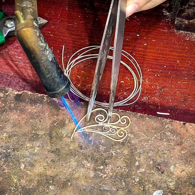 Soldering torch with a long blue flame over a silver wire creation at Silver Soul, one of the most unique things to do in Hanoi Old Quarter.