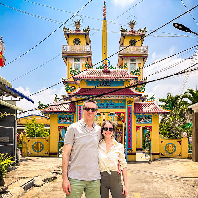 James & Shal outside the yellow Thu Thua Cao Dai Temple in the Mekong Delta, Vietnam.