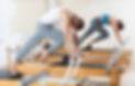 Concentrated athletic young man performing set of pilates exercises on reformer during gro