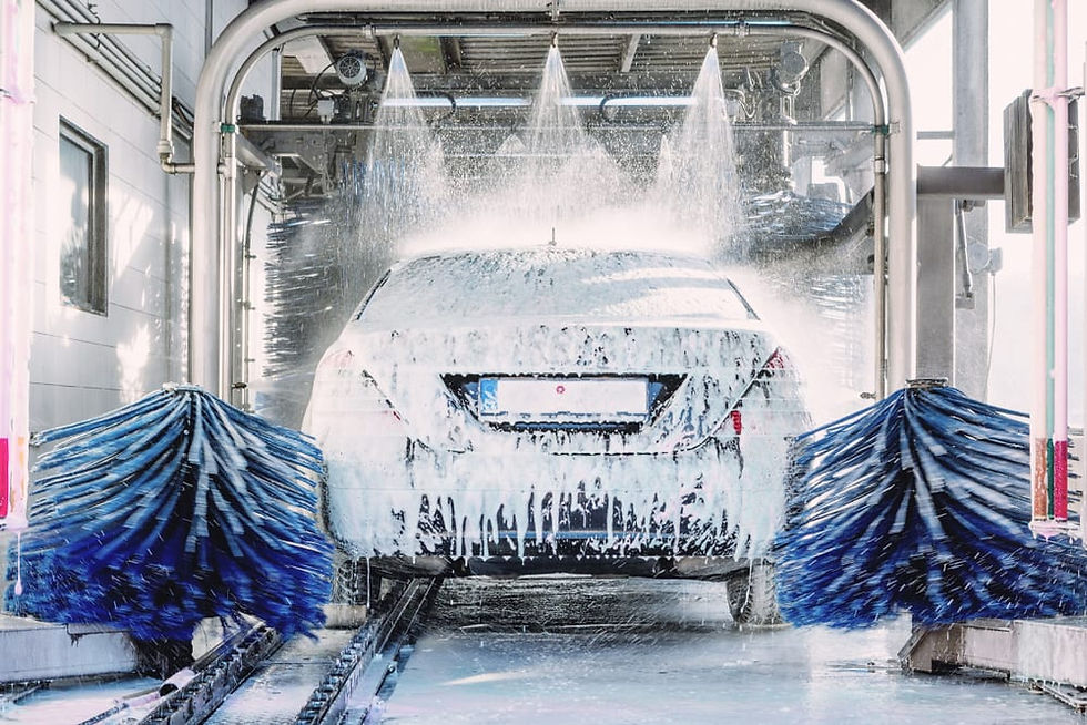 Eye-level view of a car being washed with soap and water at an automatic car wash