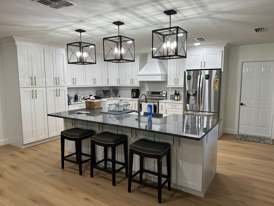 Modern kitchen with dark wood cabinets, stainless steel appliances, pendant lights, and island. Expert residential and commercial electrical work.