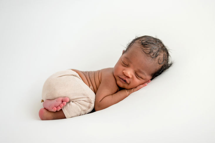 Photo d'un petit bébé nouveau-né métisse qui dort, posé sur le ventre