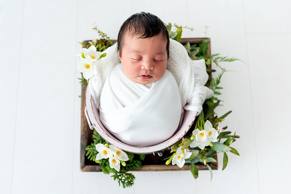 Photographe nouveau-né Nantes, Photographe bébé Nantes, Photographe naissance Nantes, Photographe studio Nantes, bébé emmaillloté couché dans un seau entouré de fleurs blanches
