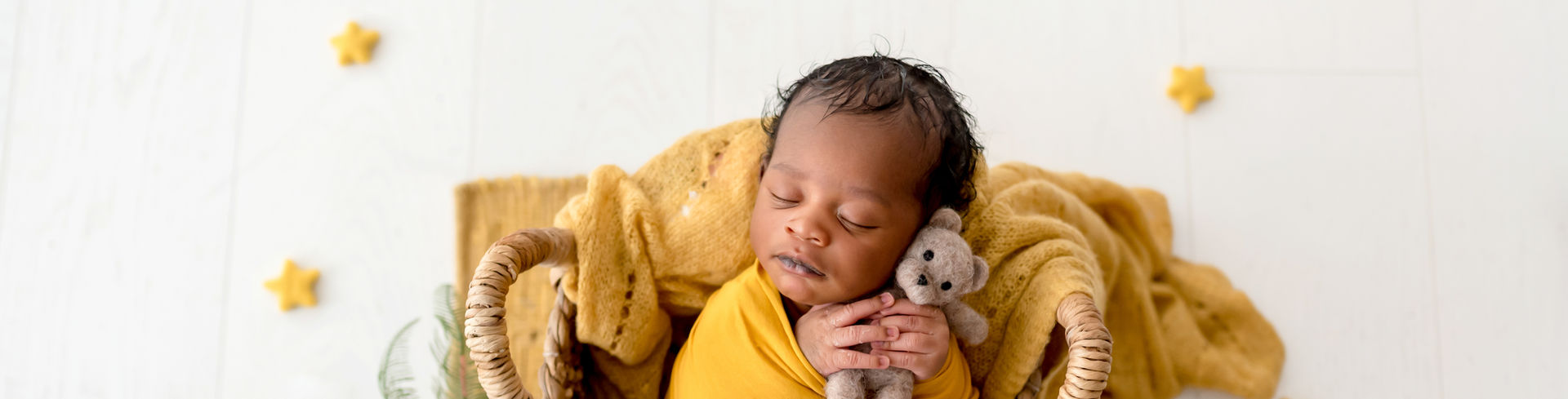 Photo d'un petit bébé métisse nouveau-né qui dort dans un panier entouré d'accessoires jaunes