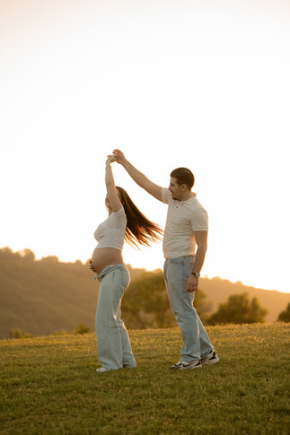 Mom holding baby bump sitting on a dock during maternity session