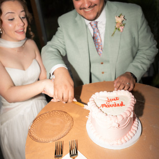 Bride + Groom cutting cake that says "just married"  at reception