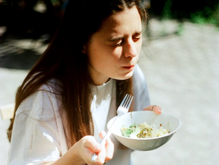 woman eating from a bowl with eyes closed