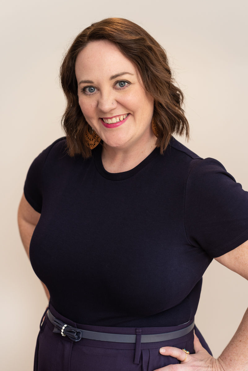 Coach, Rebekah King, standing with hands on hips, looking at the camera and smiling.